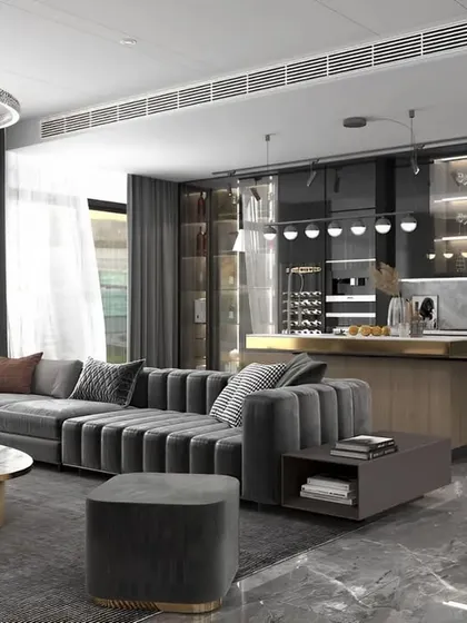 An open-concept living and dining area designed for luxury and comfort. The space features a plush, channel-tufted grey sofa, a modern kitchen island with bar seating, and elegant lighting fixtures that tie the whole look together.