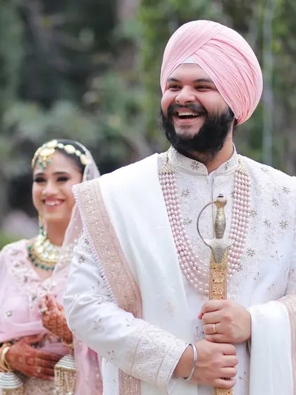 A candid shot of the groom laughing heartily while the bride smiles in the background, capturing a moment of pure, unscripted joy during their wedding day.