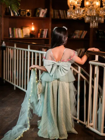 A full view of the back of this beautiful festive dress. The flowing fabric and intricate details are showcased against the warm, ambient light of the studio, creating a magical, storybook feel.