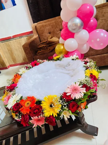 A close-up of the welcome baby cradle, beautifully decorated with a ring of fresh, colorful flowers.