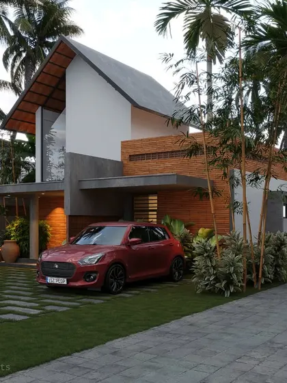 A Kasargod residence where a high, sloping roof and wood cladding meet a contemporary concrete structure, creating a dynamic exterior.