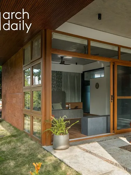 The master bedroom墙 is clad in laterite stone, a natural and locally sourced material. The large windows and door open up to a private garden space on the first floor.