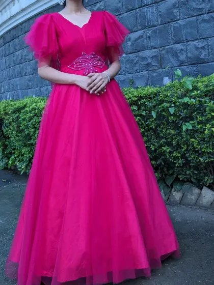 A full view of the hot pink gown with delicate butterfly sleeves and an embellished belt. It's a simple, elegant, and vibrant choice for any celebration.