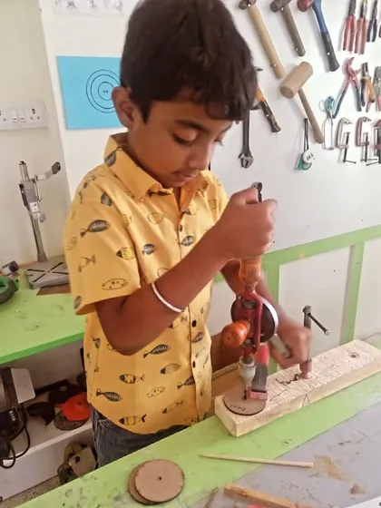 Another student masters the hand drill, a key tool in our woodworking projects. We ensure they learn through direct, hands-on application.
