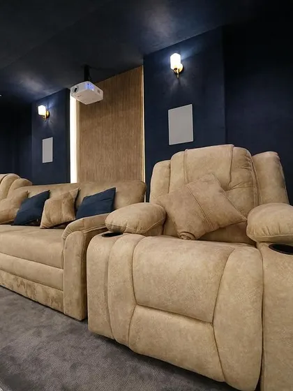 A closer look at the main seating area, with a comfortable sofa flanked by two motorized recliners, all upholstered in a soft, warm-toned fabric.