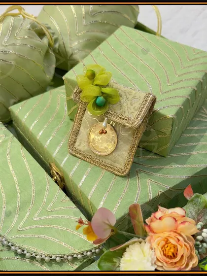 Custom wedding gifts that spark intrigue and charm. This set features gift boxes and matching clutch-style envelopes in a lovely sage green with delicate gold patterns, perfect for presenting 'shagun' or other keepsakes.