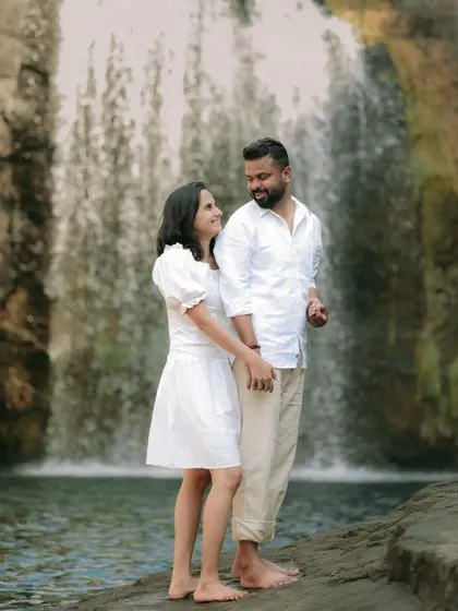 A romantic portrait of the couple in matching white outfits against the beautiful backdrop of a waterfall.