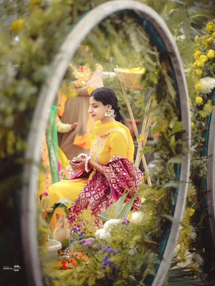 A beautifully framed shot of the bride during her Haldi ceremony. The floral decor creates a natural frame, drawing attention to her serene expression.