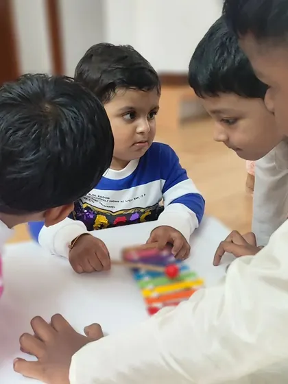 Children of different ages gather around a single activity, demonstrating the cooperative spirit of our mixed-age classrooms. The environment encourages collaboration and peer learning.