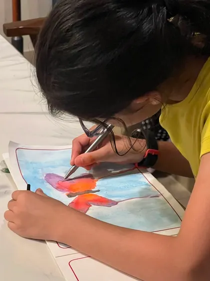 A moment of quiet concentration while painting a butterfly. Our classes help children develop focus and patience as they work on their art.
