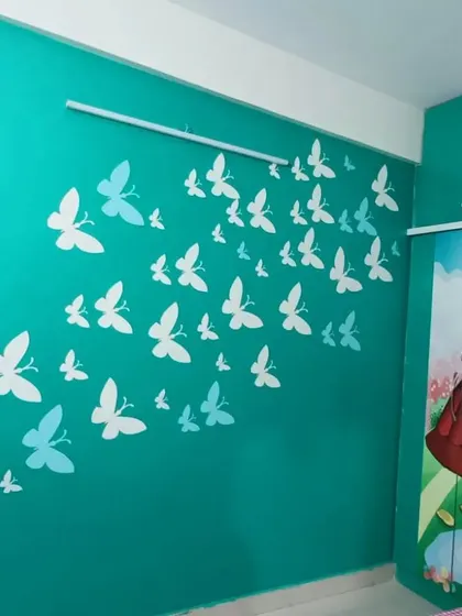 A flight of butterfly stencils in white and light blue sweeps across a vibrant teal wall, creating a whimsical and cheerful look for a child's room.