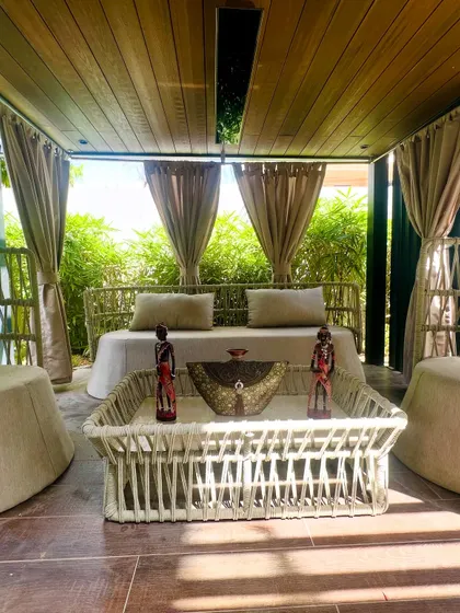 The symmetrical arrangement of the furniture inside the pergola creates a balanced and inviting composition. The open view connects the lounge directly with the surrounding garden.