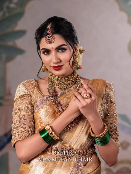 A beautiful shot of the bride smiling, with her hands gracefully posed. The green bangles provide a stunning contrast to the golden saree.