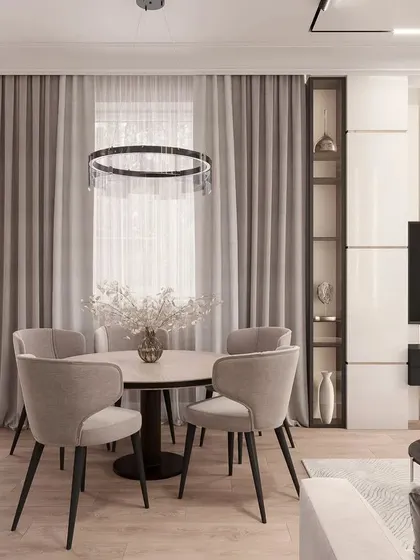 A closer look at the dining area, featuring a modern ring chandelier that acts as a centerpiece without obstructing the view. The built-in shelving unit provides a stylish display space while maintaining the room's clean aesthetic.
