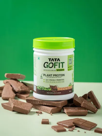 A creative product shot for a chocolate-flavored protein powder, surrounded by chunks of chocolate to visually reinforce the flavor profile.