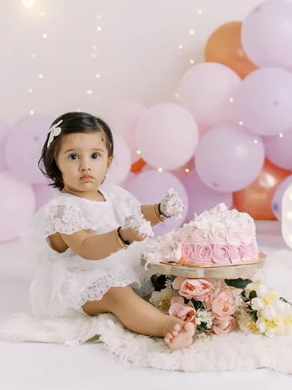 A little girl gets her hands messy during her first cake smash. I love her focused expression as she explores the cake.