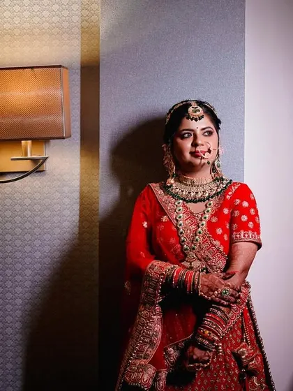 A full-length portrait of the bride in her stunning red lehenga. The dramatic side lighting creates a sophisticated and elegant look, highlighting the rich texture of her outfit. (Similar to 56)