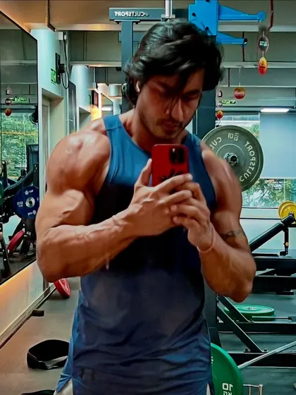 A focused gym selfie showcasing the results of consistent training. Every detail, from shoulder striations to forearm veins, is earned.