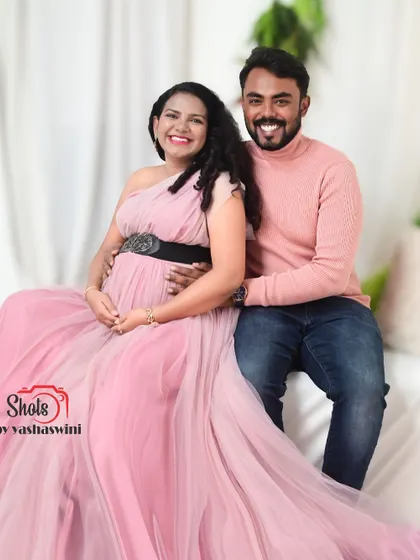 This happy couple is creating beautiful memories with our pink one-shoulder maternity gown during their indoor photoshoot.