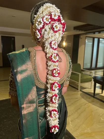 A detailed view of the stunning South Indian bridal braid, intricately woven with fresh jasmine and red flowers. It's a true work of art.