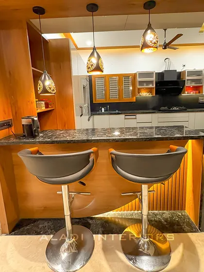A close-up of the breakfast bar, showing the comfortable modern stools and the elegant pendant lights that define the seating area.