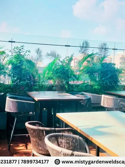 The rooftop dining area at Skydeck, with a border of lush plants set against a glass railing, offering diners a beautiful green view of the city.