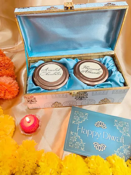 An open view of our blue patterned trunk box, revealing two jars for assorted chocolates and flavored almonds.