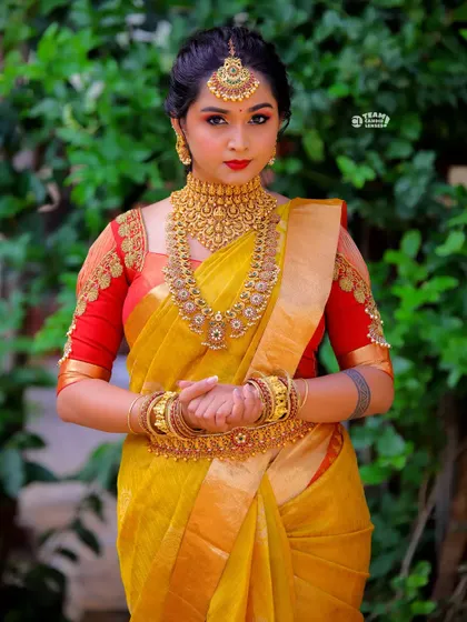 This jewellery-inspired maggam work blouse in yellow and red is designed to mimic a necklace, creating a seamless and opulent look for a bride.