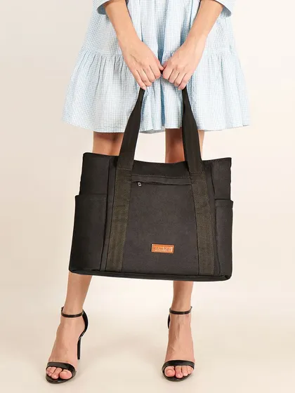 A model holding a large black tote bag. This lifestyle shot shows the bag's size in relation to the person, which is a critical piece of information for online shoppers.