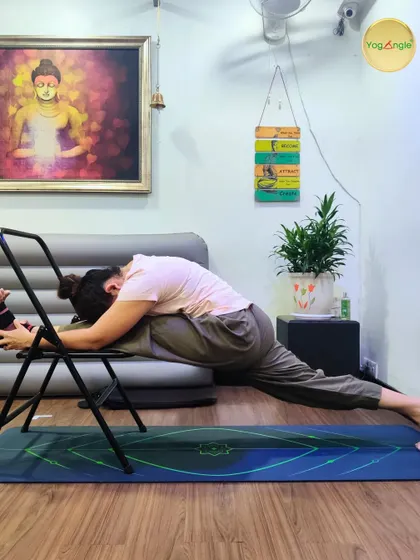 The chair is an excellent tool for working on advanced flexibility. Here, a student practices Hanumanasana, or the front splits, using a chair for support. This allows for a gradual and safe release into this deep hamstring and hip flexor stretch.