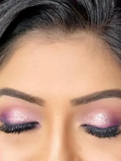 A close-up of a purple and pink glitter cut-crease. This is an advanced eye makeup technique that we teach, focusing on precision, blending, and the application of loose glitter for maximum impact.