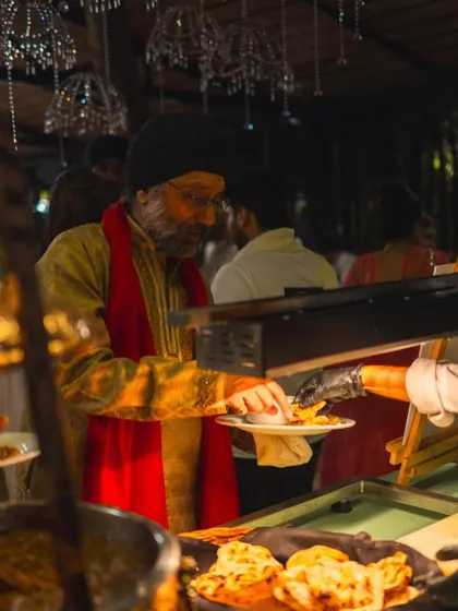 A guest enjoying the buffet, selecting from a variety of Indian breads and curries.