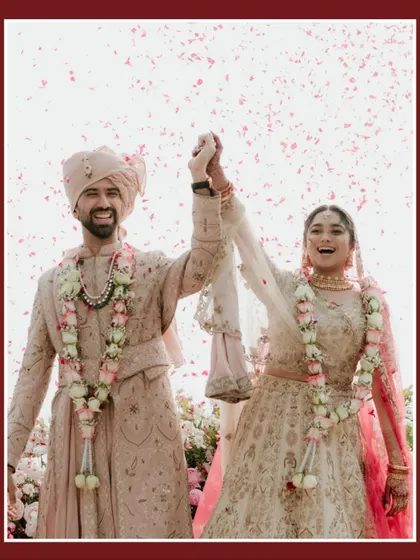 The triumphant "just married" moment. The couple holds hands, their faces lit up with joy as they are showered with flower petals by their loved ones.