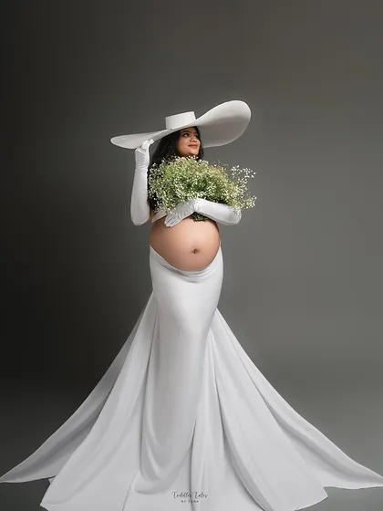 The color version of the elegant white gown with a flowing train and statement hat. Paired with a bouquet of baby's breath, this look is the epitome of grace in bloom.