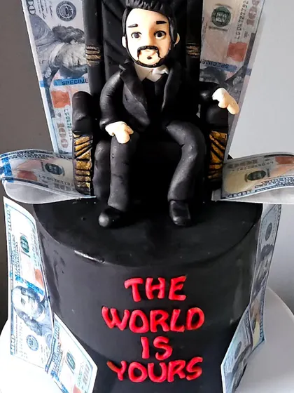 This shot highlights the edible figurine topper on the black fondant cake. The contrast of the red lettering and the edible dollar bills makes for a very dramatic and impressive design.