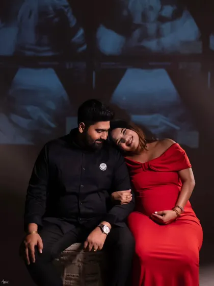 A relaxed and happy portrait of the couple with their sonogram projected behind them. Her head resting on his shoulder shows their comfort and closeness during this exciting time.