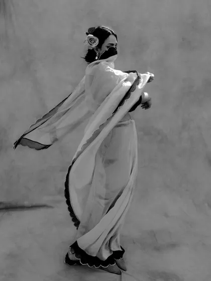 A black and white photograph capturing the fluid motion of a dancer in a flowing saree, creating an elegant and timeless silhouette.
