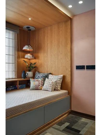 We transformed a spare bedroom into a cozy family nook. A comfortable bay window seat is set against a soft pink lime-washed wall, creating the perfect corner for reading and relaxation.