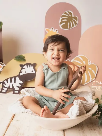 A big, gummy smile from the birthday boy, sitting in a white bowl amidst his jungle friends.