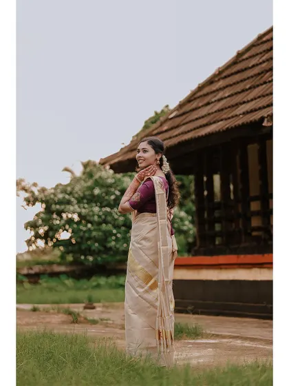 An elegant three-quarter portrait of the bride in her beautiful kasavu saree.