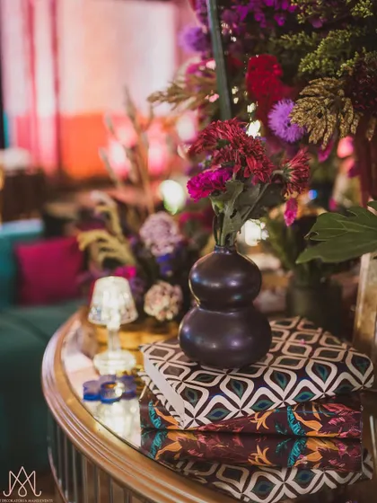 A close-up of a centerpiece, showing the mix of textures from the flowers, the vase, and the custom-printed books they are placed on.
