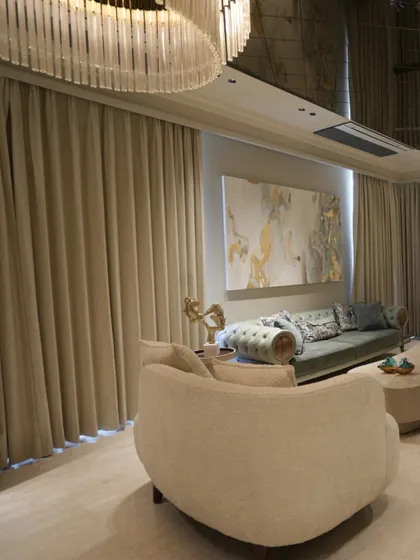 From this angle, you can see how the floor-to-ceiling curtains soften the room and complement the neutral color palette. The large painting and custom sofa create a well-balanced and inviting living area.