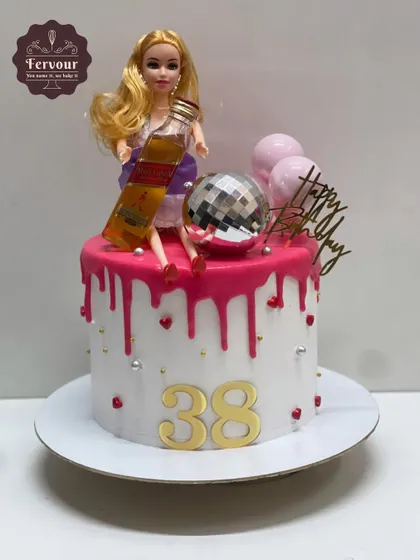 A fun and cheeky Barbie-themed cake for a 38th birthday. This design features a Barbie doll with a miniature bottle of Johnnie Walker Red Label, a disco ball, and a pink drip.