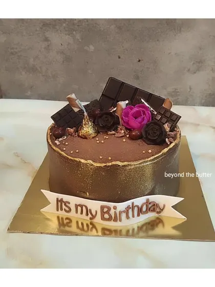 A special birthday cake for a chocolate lover, decorated with chocolate bars, Hershey's Kisses, and a single pink rose for a pop of color.