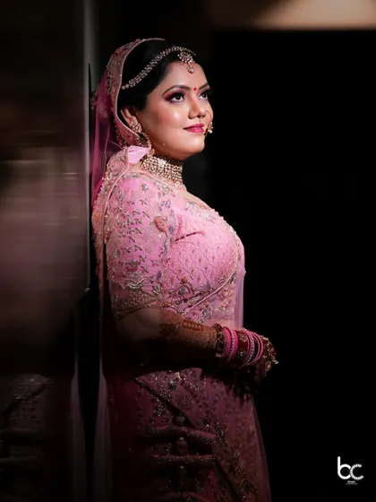 An elegant side-profile portrait of the bride in her pink wedding lehenga, captured in a moment of quiet reflection.