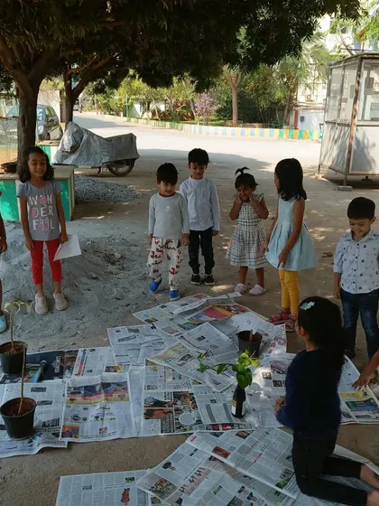 Children stand around their outdoor workspace, ready for a gardening project. Learning outdoors provides a different kind of sensory experience and a connection to the natural world.
