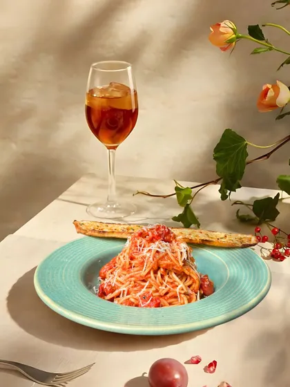 A beautifully plated spaghetti dish, paired with a refreshing drink. This is what a perfect, indulgent meal looks like at Fat Lulu's.