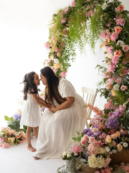 A sweet nose-to-nose moment between a mother and daughter amidst the flowers. The floral setup creates such a dreamy and romantic atmosphere.