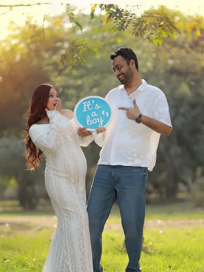A candid and joyful gender reveal moment. The mother-to-be's surprised and happy expression is perfectly captured in the beautiful outdoor light.