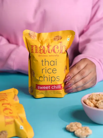 A lifestyle shot for Natch's Thai Rice Chips, using color and a human element to create a relatable and vibrant image for social media.